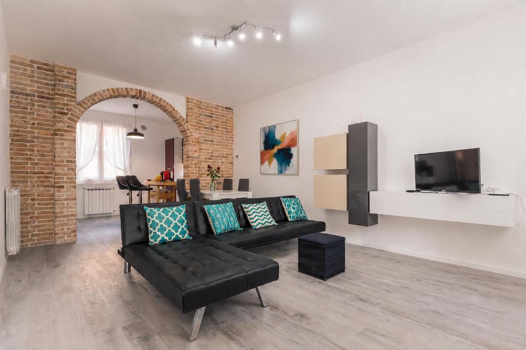 a living room with a black couch and a tv at CaMagnolia Apartment in Montegrotto Terme