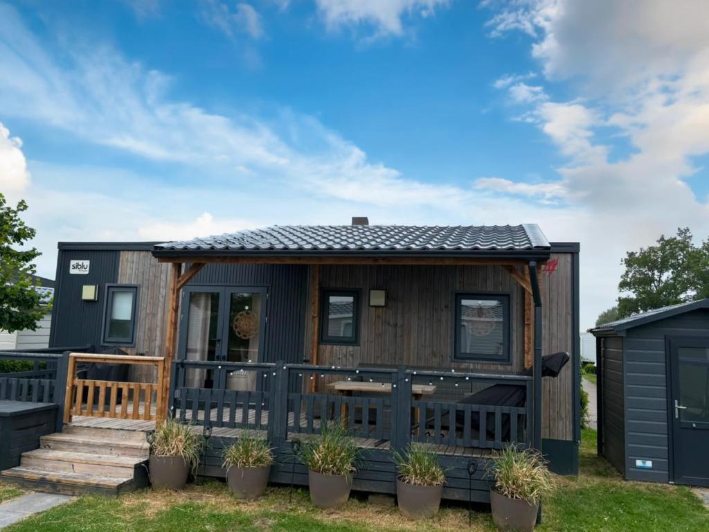 a tiny house with a porch and a deck at Camping in de Bongerd - Kust&Q in Oostkapelle