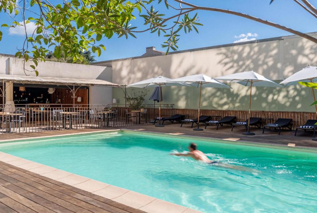 a man swimming in a swimming pool at Best Western Hotel le Galice Aix-en-Provence in Aix-en-Provence