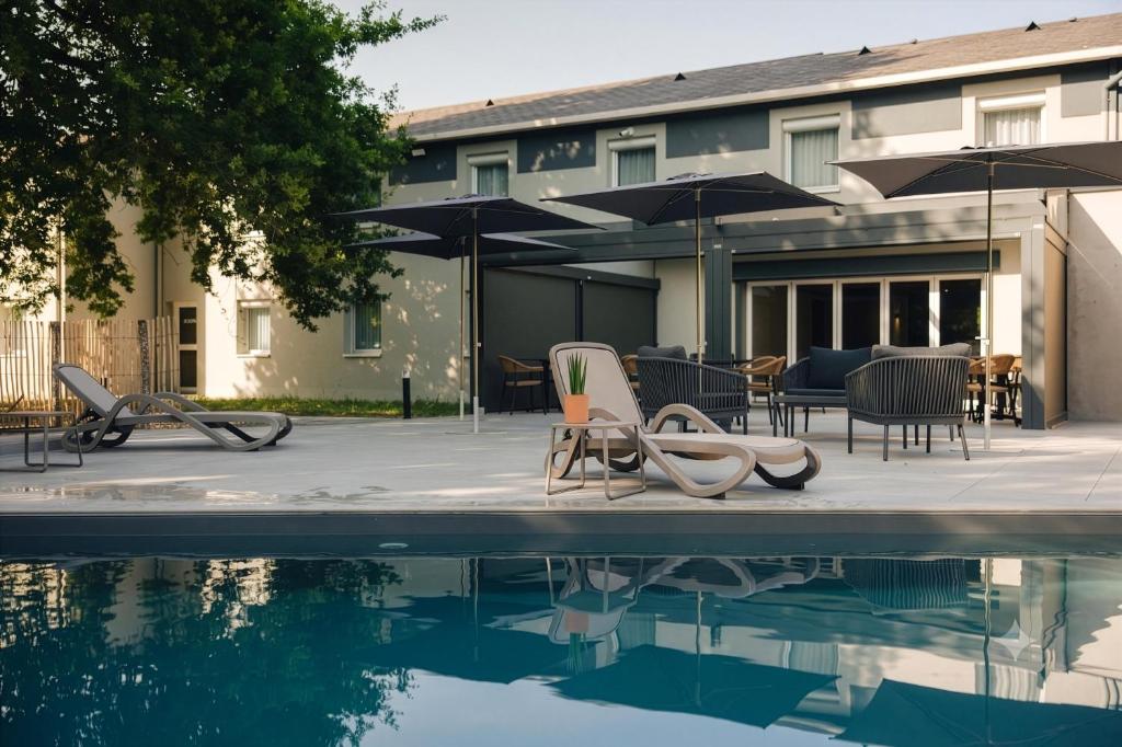 a pool with chairs and umbrellas next to a building at Sure Hotel by Best Western Tours Sud in Chambray-lès-Tours
