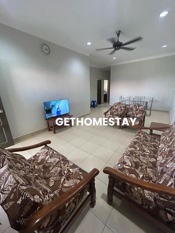 a room with three beds and a tv on the wall at Gethomestay Keningau in Keningau