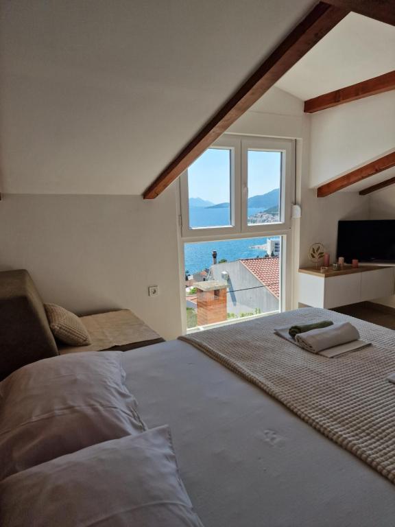a bedroom with a large bed with a large window at Apartmani Mandić in Neum