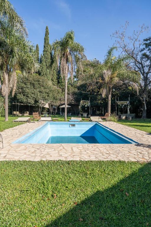 a blue swimming pool in a park with palm trees at Casa Campo Hotel Boutique - San Pedro in San Pedro