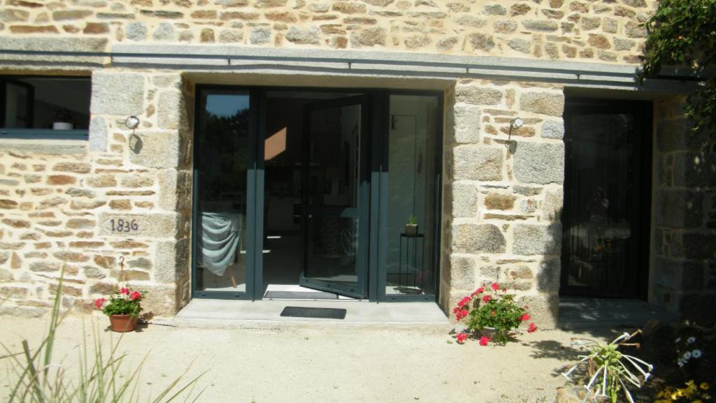 an open door of a stone building with flowers at L'Etable d'Armand in Névez