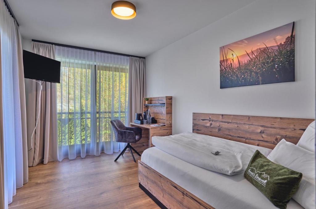 a bedroom with a bed and a desk and a window at Annies Bergwelt Haus Waldliebe in Bodenmais