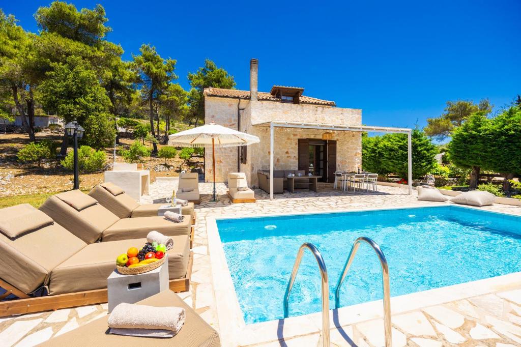 an outdoor swimming pool with chairs and a villa at Villa Boscheto Tria in Agios Leon