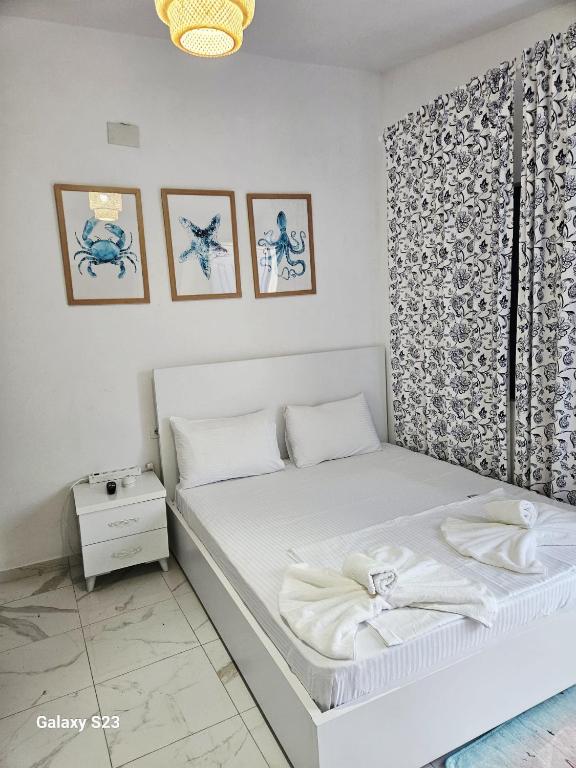 a small bedroom with a white bed and pictures on the wall at Cozy Family Studio 2 in Ksamil