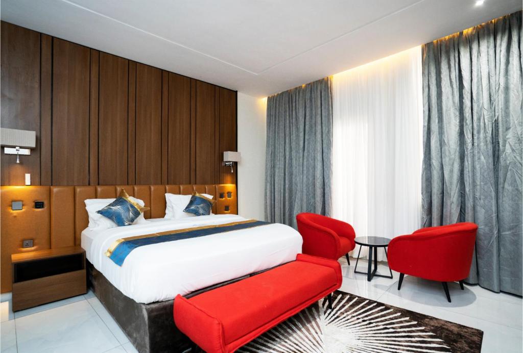 a hotel room with a bed and a red chair at Oxvera Hotel Limited in Umuahia