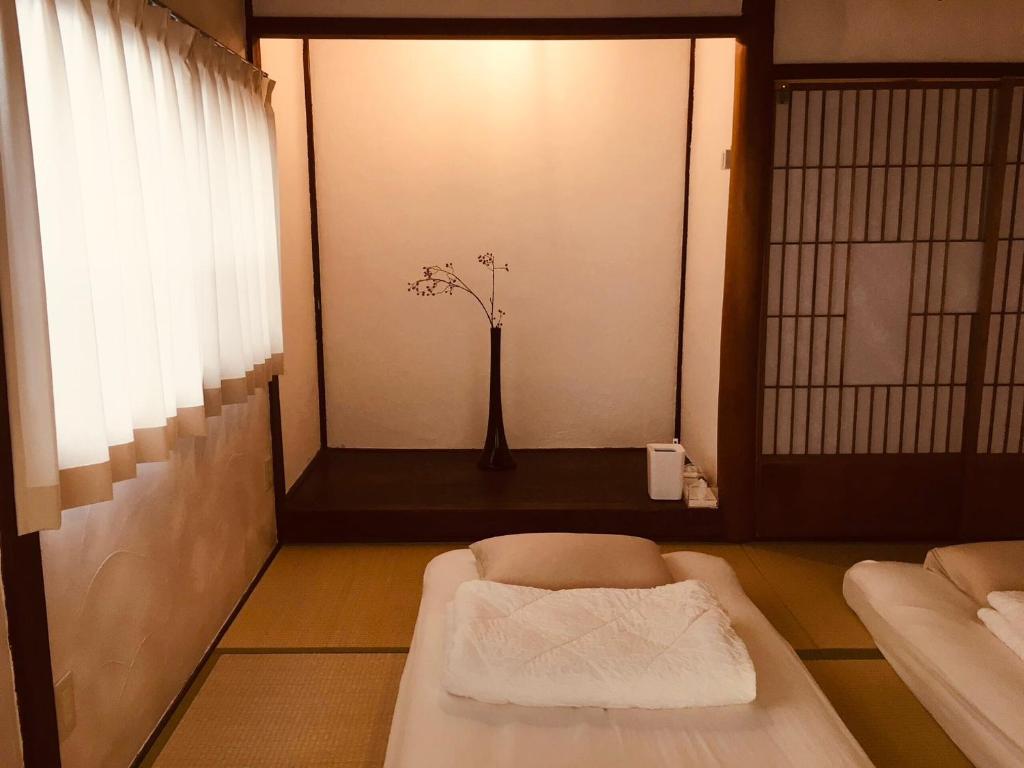 a room with a bed and a vase with flowers in it at 貸切一軒家 祇園House in Matsuyama