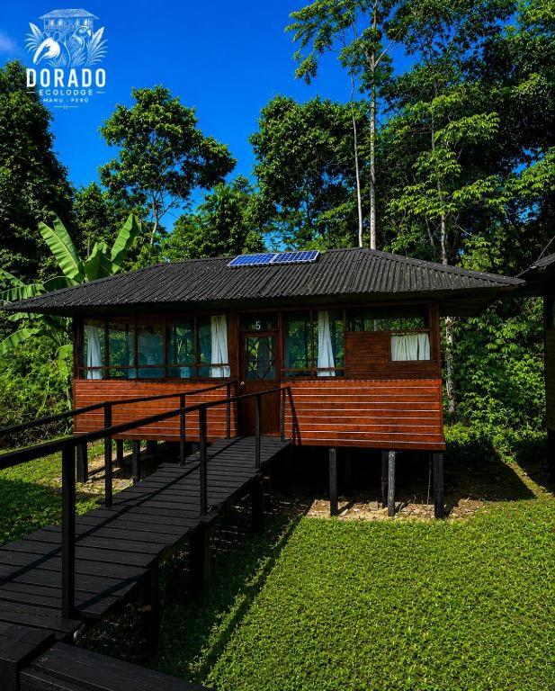 a small house with a deck in the grass at Dorado Lodge in Manú