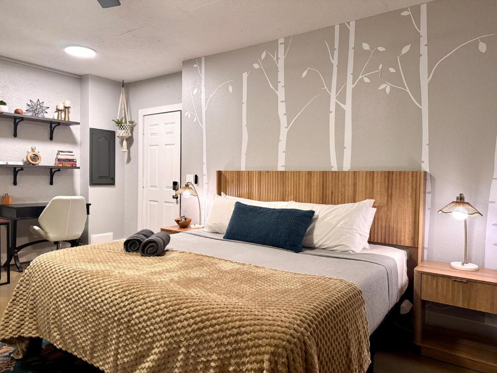 a bedroom with a bed with a blanket and trees painted on the wall at Set on peaceful 5 acres, 5 min from town, Private Building, Level 2 EV Charger in Bloomington
