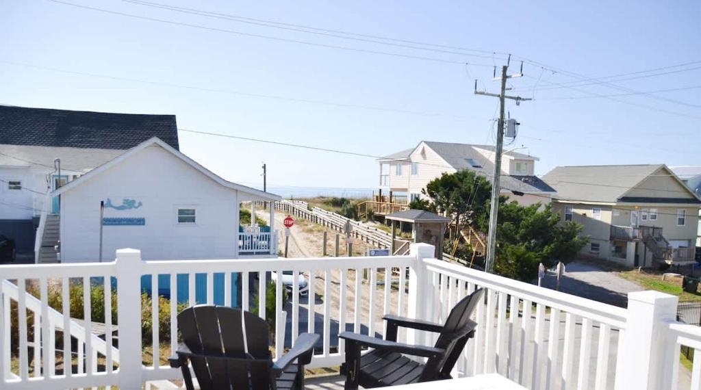 a balcony with two chairs and a white railing at Oceanfront Townhouse steps to the Beach in Atlantic Beach