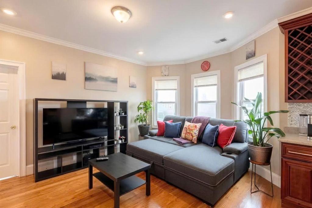 a living room with a couch and a flat screen tv at Vibrant 4BR Boston Apt - Balcony, Bathtub, TV near I-95 & Pet Friendly 903 in Boston