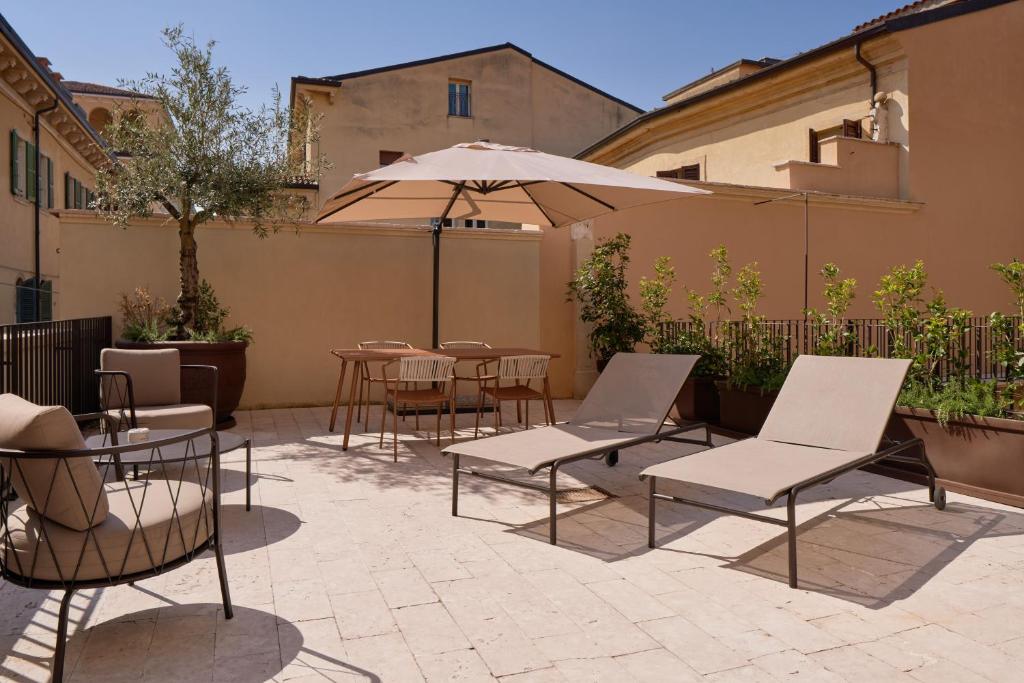 a patio with tables and chairs and an umbrella at Homy Livia Verona in Verona