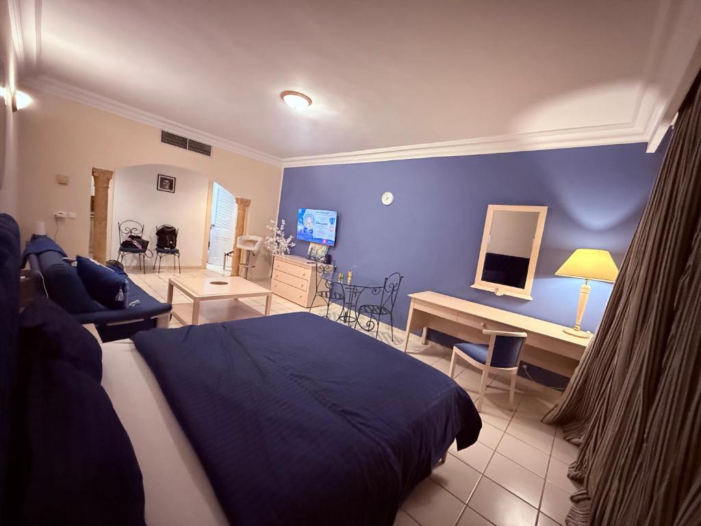 a bedroom with a blue wall and a bed and a desk at Yasmina Hotel Appartment in Yasmine