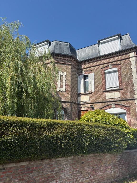 a brick house with a hedge in front of it at La briqueterie in Bourseville