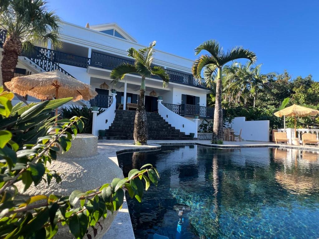 a resort with a swimming pool and palm trees at La Belle du Sud in Saint-Joseph