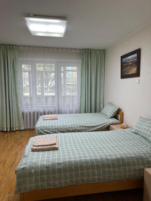 two beds in a room with green curtains at Cozy 2 BR Apartment with Easy Access in Ulaanbaatar