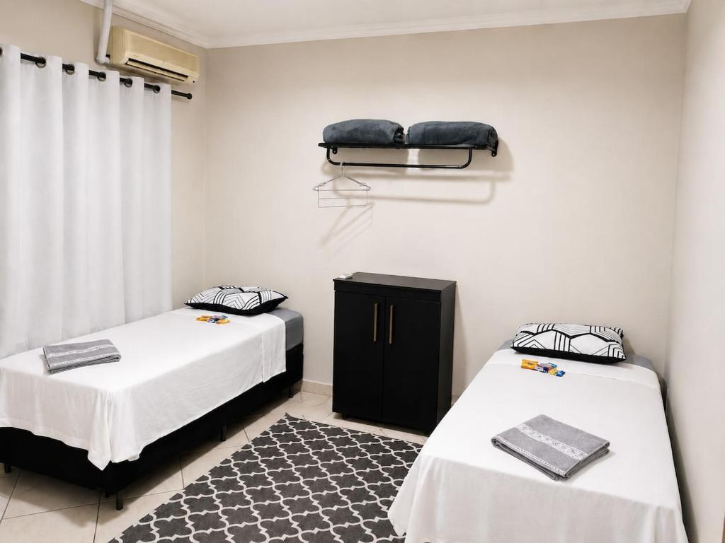 a bedroom with two beds and a rug at Studio aconchegante com ar-condicionado e Smart TV in Bauru