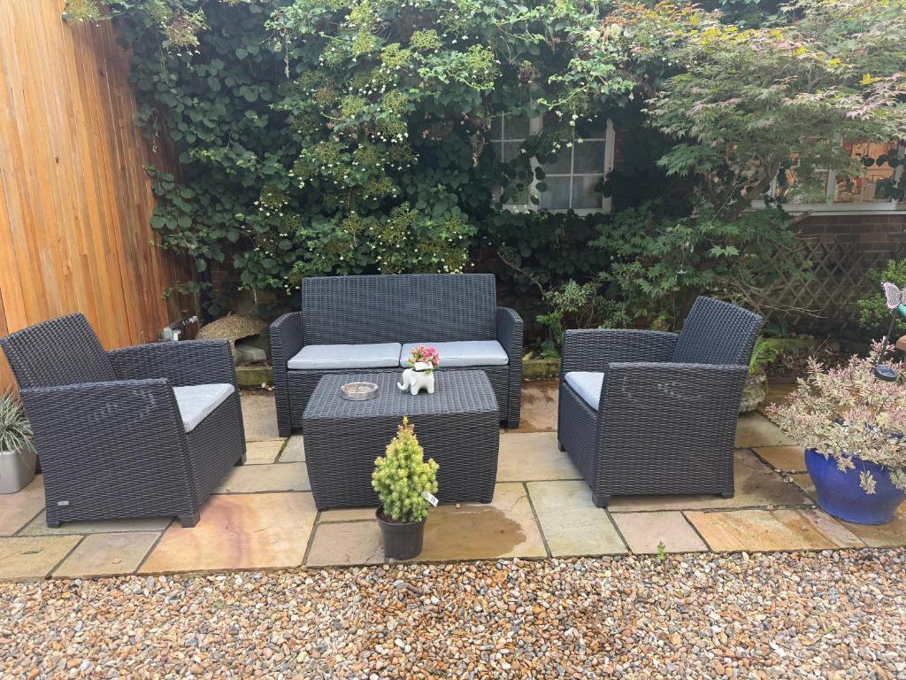 a patio with three wicker chairs and a table with a plant at Da Vinci Guest House Gatwick Guest Parking, A Real Gem in Crawley