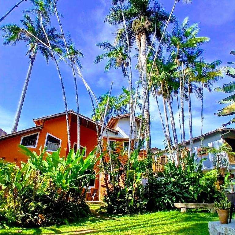 a house with palm trees in front of it at Villa dos Pássaros Paraty Hospedagem in Paraty