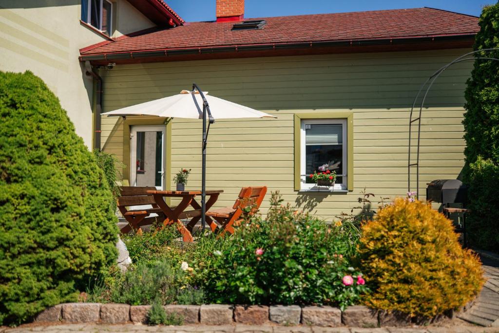 a house with a wooden table and an umbrella at Zaļais Stūrītis - Semi-Detached Holiday Home with Private entrance & Indoor Sauna in Liepāja