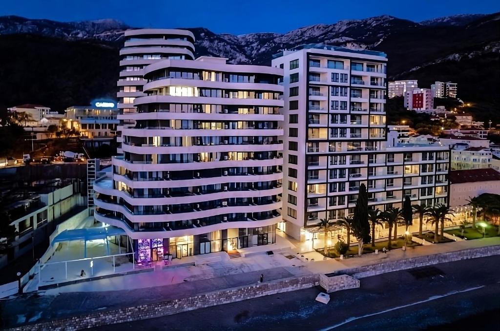 a large white building in a city at night at Azure Coast Deluxe Residence - Budva Seafront Living Suites in Bečići