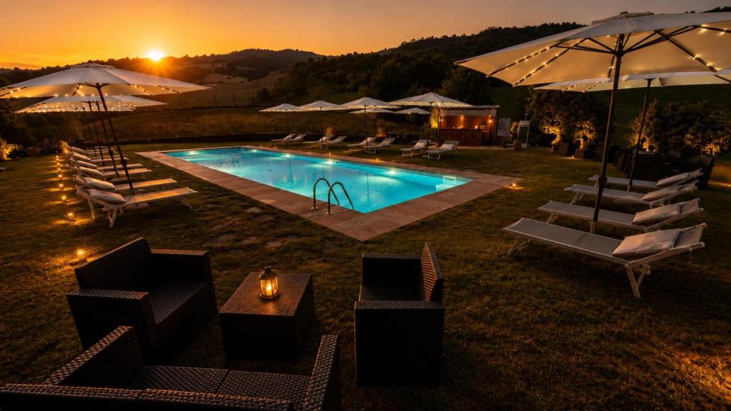 a swimming pool with chairs and umbrellas at dusk at Lodole B&B in Monzuno