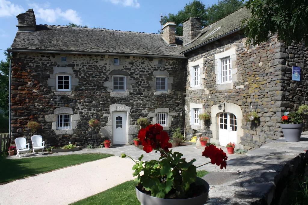 an old stone house with red flowers in front of it at La Maison De Suzanne in Arcomie