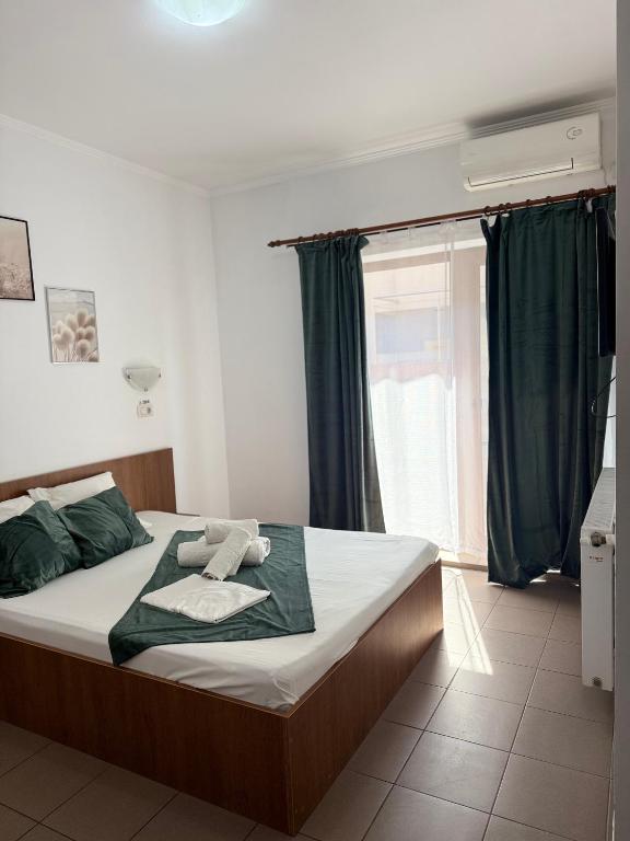 a bedroom with a bed with green sheets and a window at Vila Cristina in Mamaia Sat/Năvodari