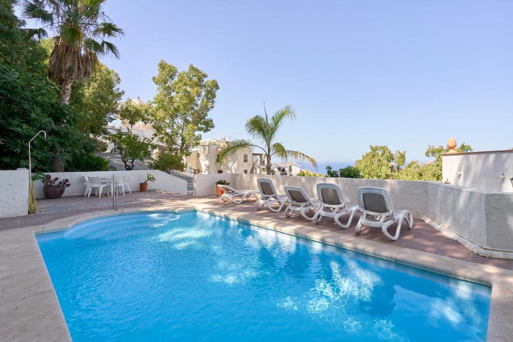 a swimming pool with lounge chairs next to a fence at Casa Trino in Almuñécar