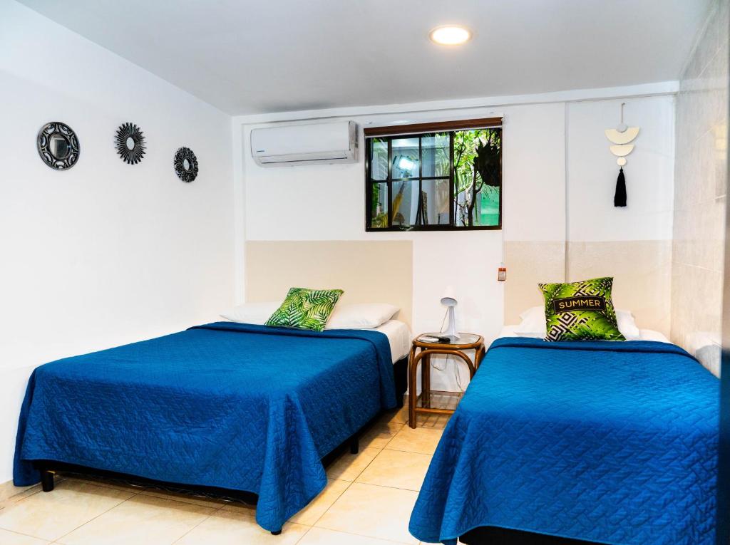 two beds in a room with blue sheets at Charlys Place in San Salvador