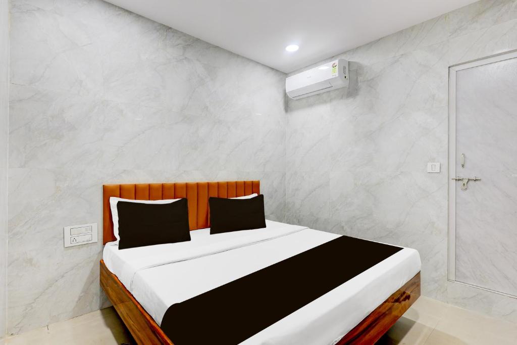 a bedroom with a large bed with white walls at Hotel O Lotus in Surat