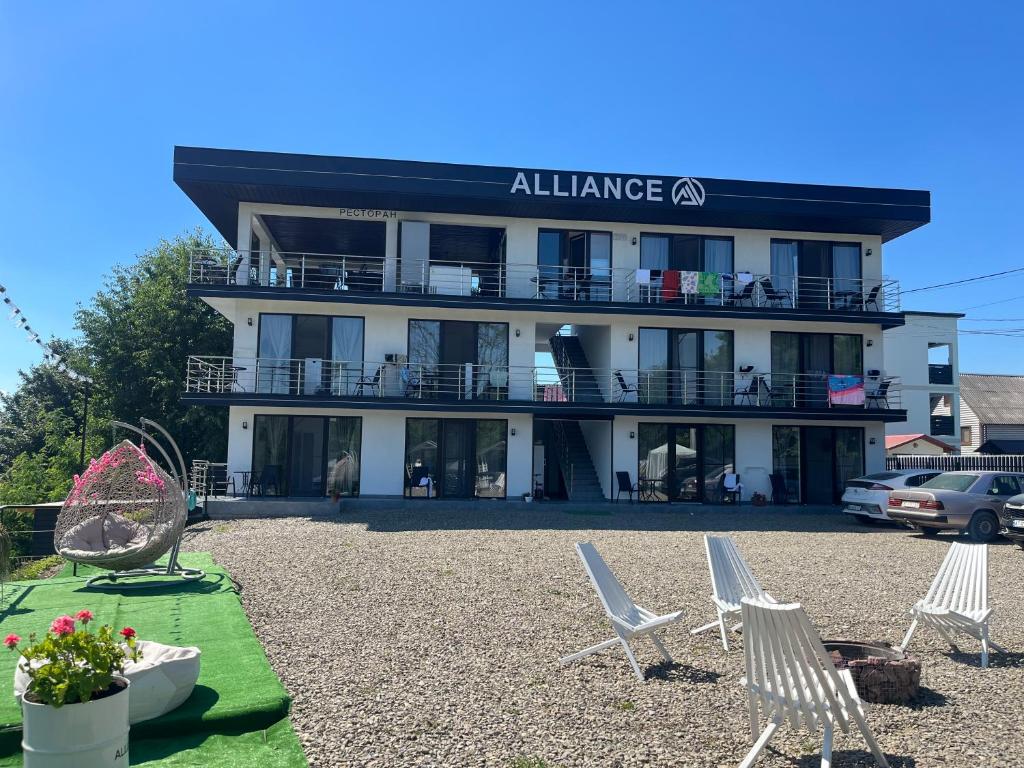 a large building with lawn chairs in front of it at ALLIANCE Hotel NEW 2025 -Breakfast and pool included in Solotvyno