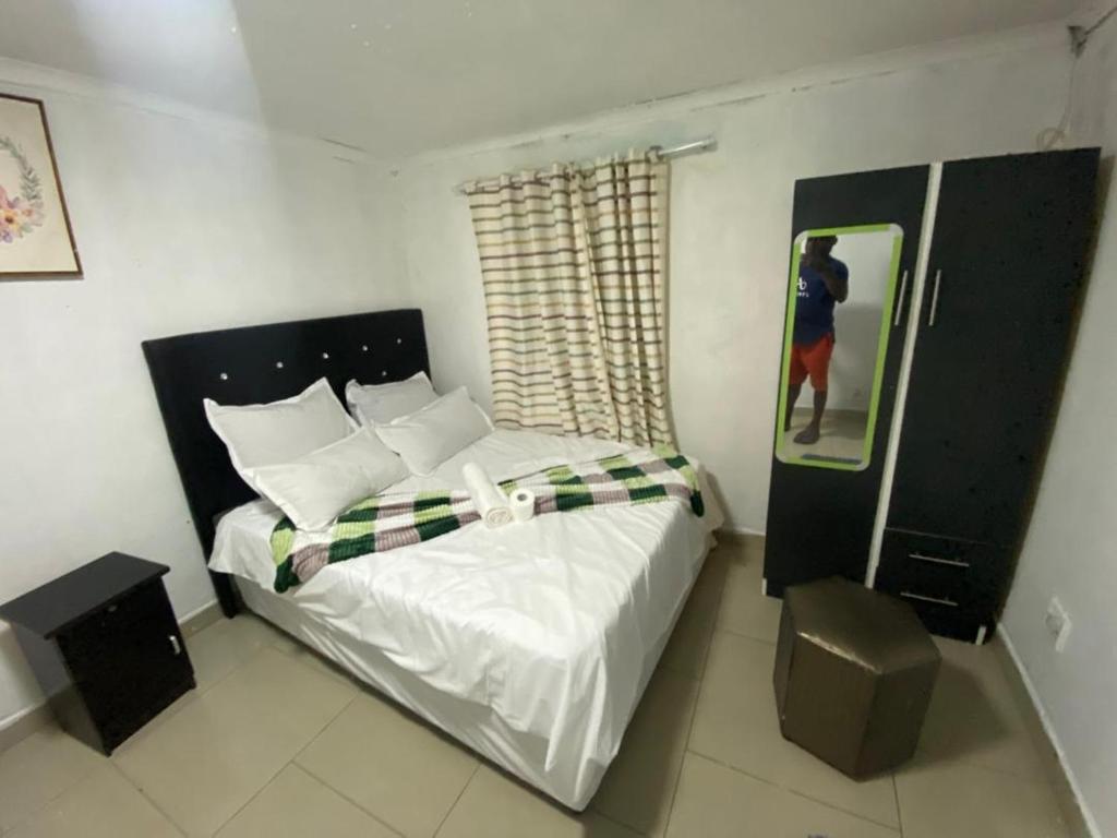 a bedroom with a bed with white sheets and a window at inspan lodge in Bellville South