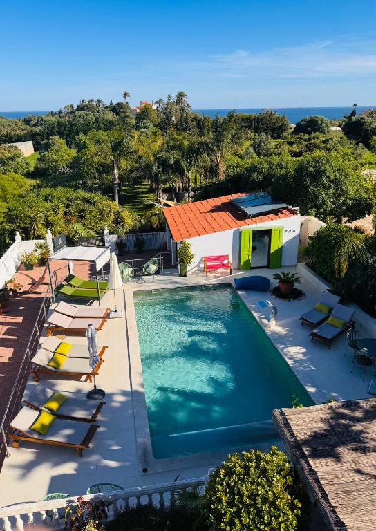 an overhead view of a swimming pool with chairs and a house at Palm View Guesthouse, adults only in Luz
