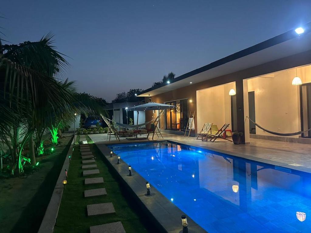 a swimming pool in front of a house at night at Ker Ar Mor - Villa 3 chambres avec piscine privée à Nguerigne in Sintiân