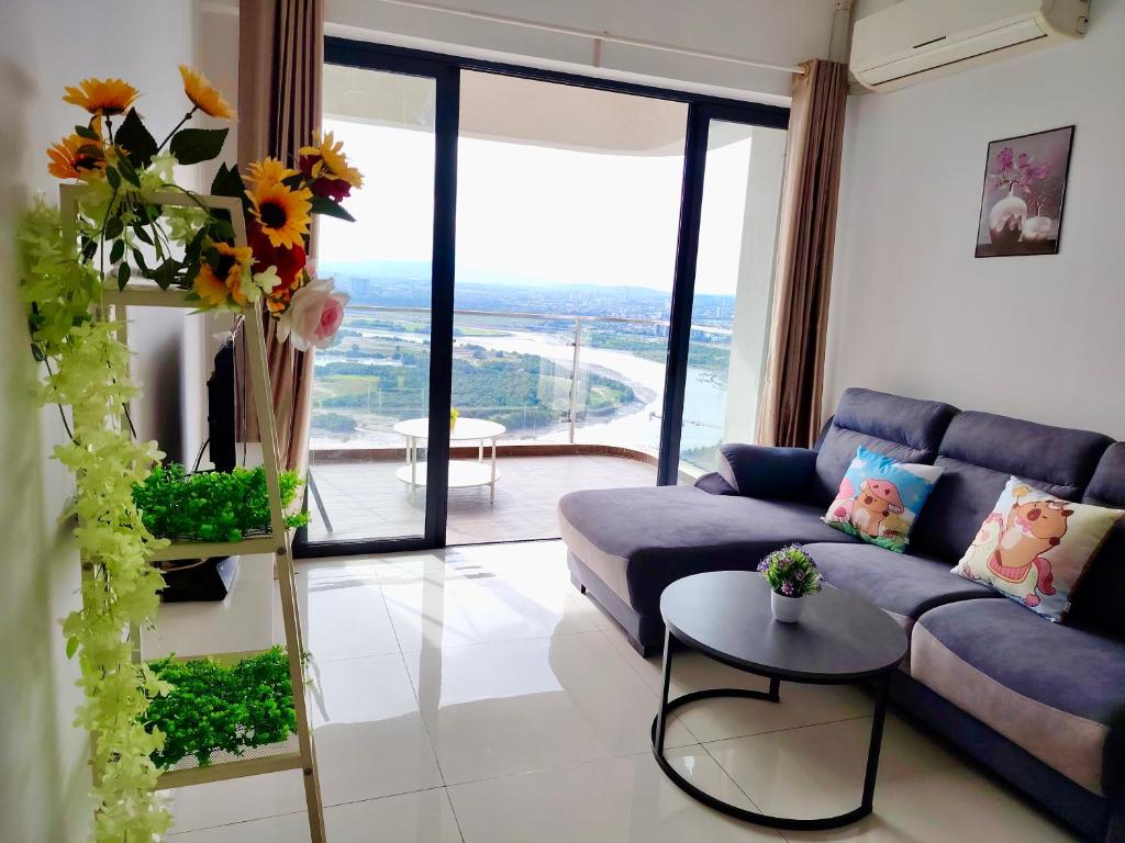 a living room with a blue couch and a large window at Amberside Coastal Breeze Oasis in Johor Bahru