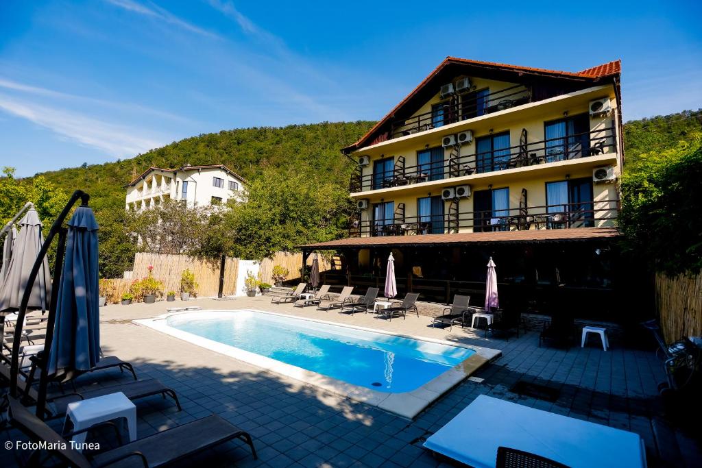 a hotel with a swimming pool in front of a building at Pensiunea Celestin in Eşelniţa