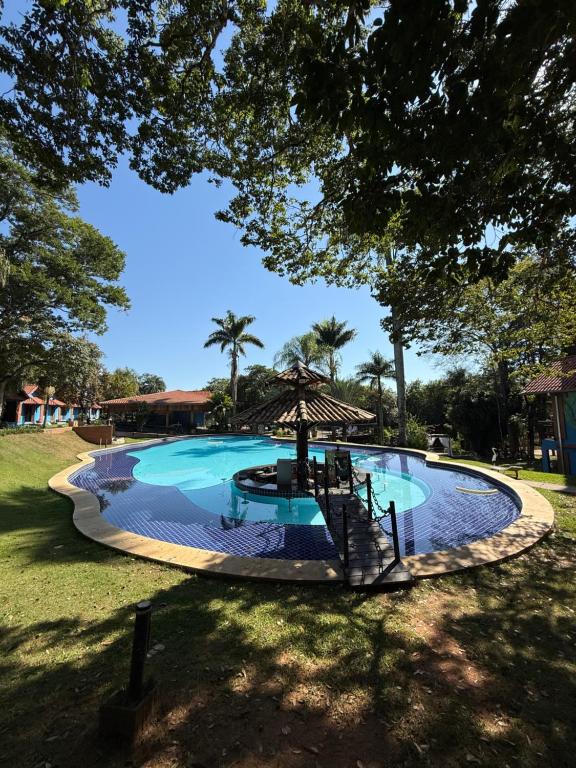 a large swimming pool with a umbrella in a yard at Hotel fazenda Floresta do Lago in Socorro