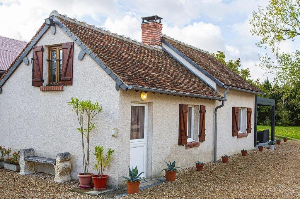 a small white house with a bench in front of it at Gîte avec jacuzzi La Halte de Chambord in Mur-de-Sologne