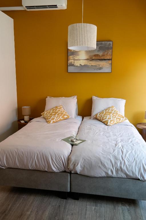 a bedroom with two beds with a yellow wall at B&B Bistro Lochem in Lochem