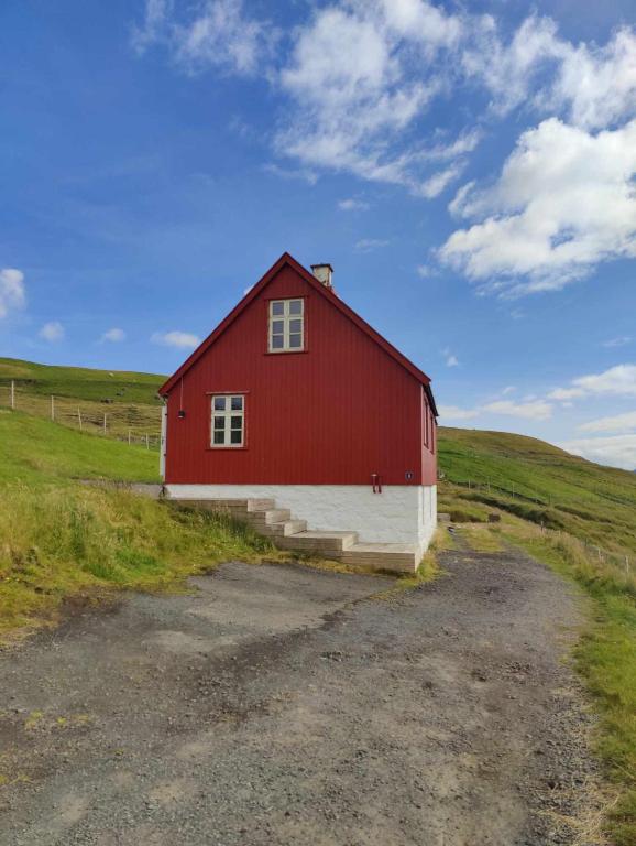 a red and white barn in a field at Charming House - Stunning views - Parking in Torkilsheyggjur