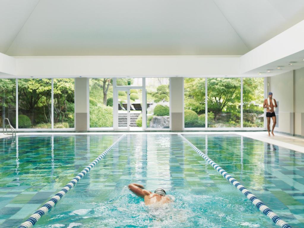 un homme nageant dans une piscine dans l'établissement Aspria Royal La Rasante Hotel & Spa, à Bruxelles