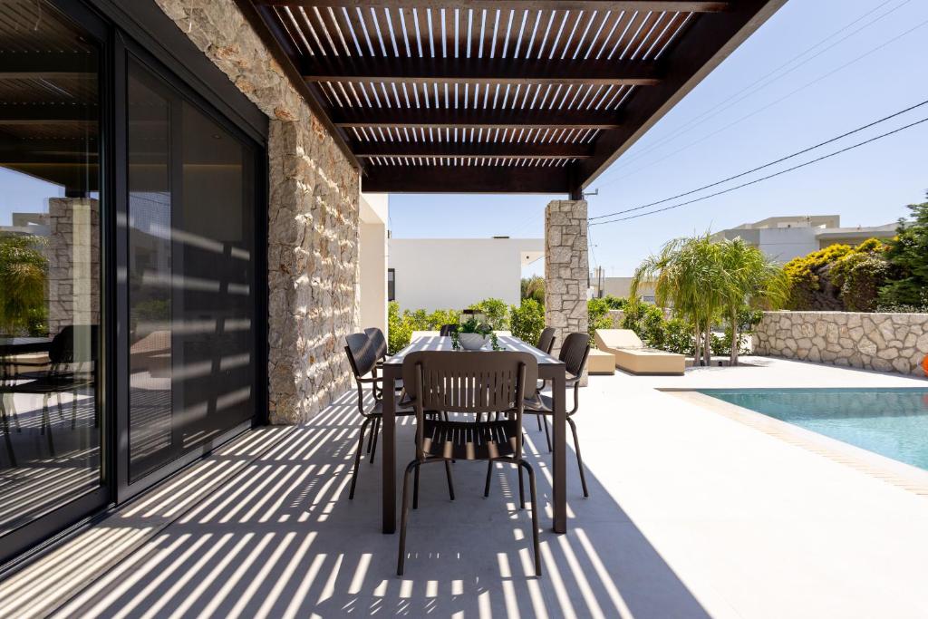 a patio with a table and chairs under a pergola at Noera Villas in Kremasti