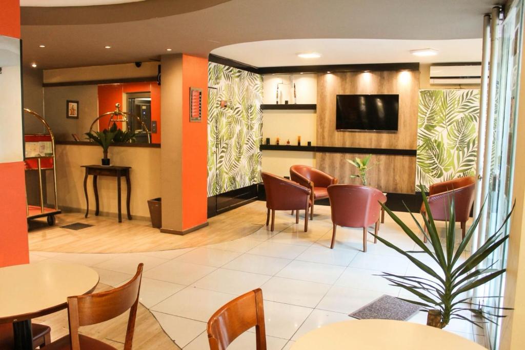 a restaurant with tables and chairs and a tv at Savannah Cordoba Hotel in Córdoba
