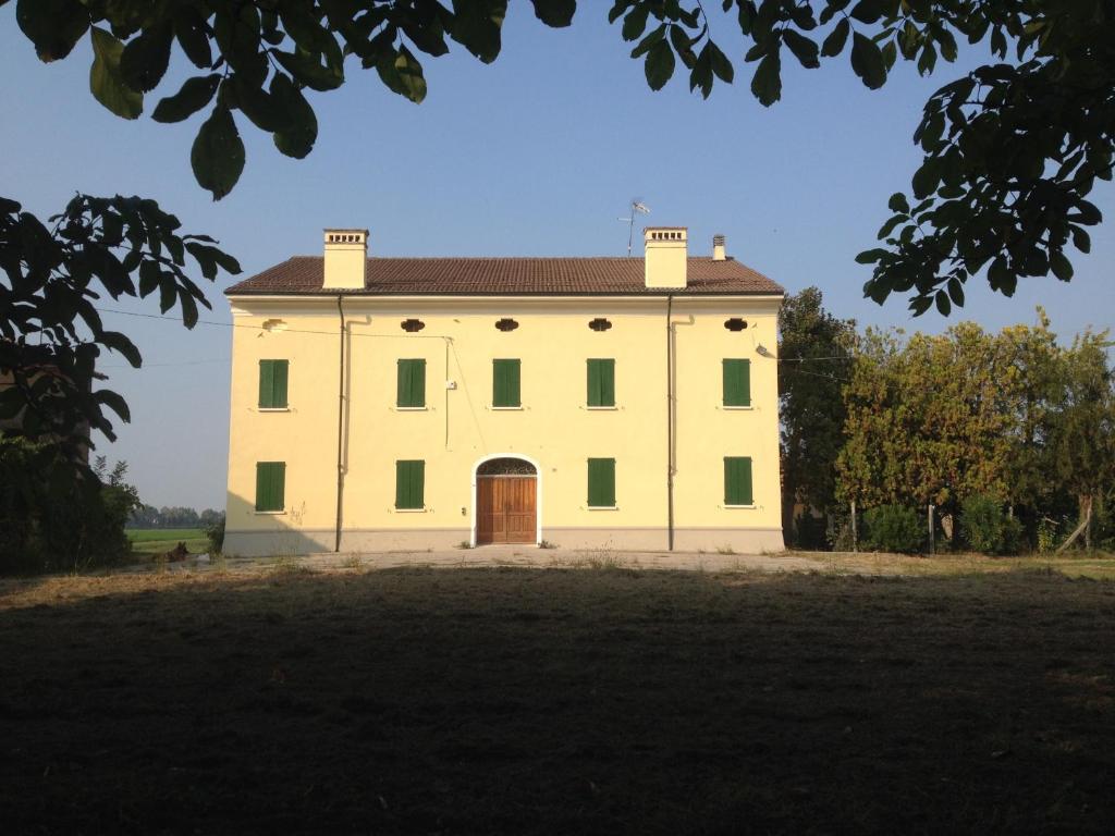 a large white building with a door in a field at Corte Croce in Gonzaga
