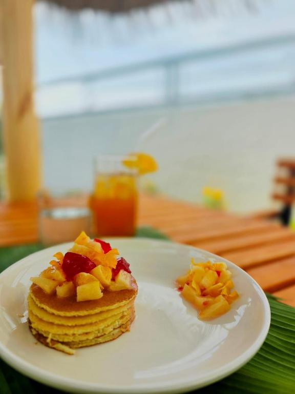 a white plate with a stack of pancakes with fruit on it at Ee Seaview Maldives in Vevaru