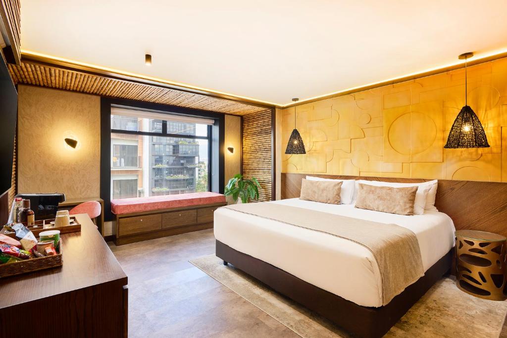 a bedroom with a bed and a desk and a window at Golden Valley Hotel in Medellín