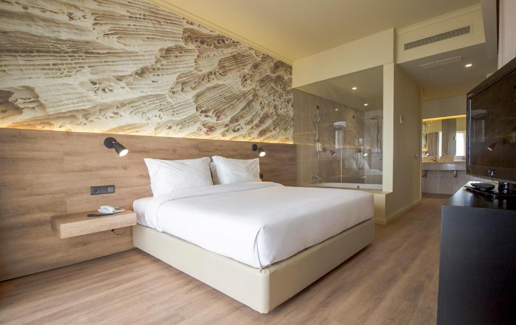 a bedroom with a large white bed and a bathroom at Calheta Beach - All-inclusive - Savoy Signature in Calheta